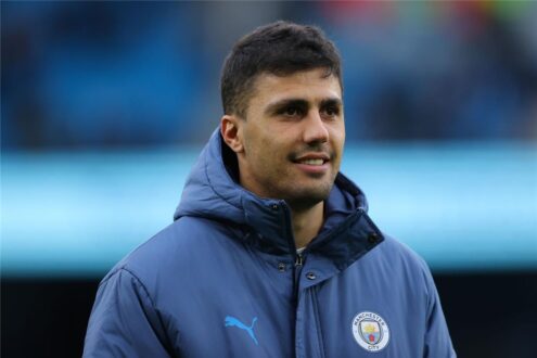 رودري لاعب مانشستر سيتي وقميص ريال مدريد مع شعار النادي