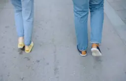 شخص يمشي في حديقة خضراء مع جهاز تتبع الخطوات، يرمز إلى النشاط البدني والصحة.