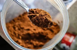 مسحوق الكاكاو الداكن في وعاء مع حبوب الكاكاو، يرمز لفوائده الصحية للقلب والمزاج.