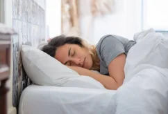 شخص ينام على جانبه بوضعية صحيحة مع وسادة بين الركبتين لتخفيف آلام الظهر