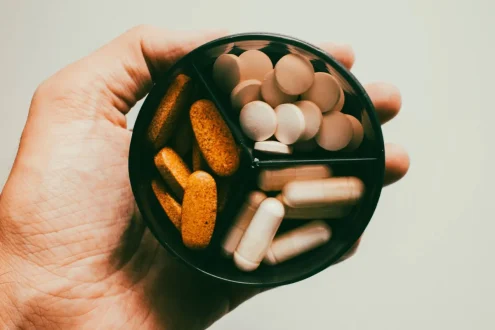 شخص يحمل أنواعاً متعددة من المكملات الغذائية مع علامات استفهام حول الإسهال.